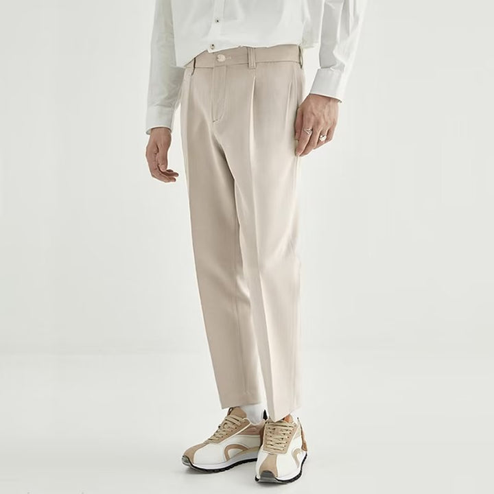 Close-up of men's high-waisted pleated cropped dress pants fabric, showing texture and pleat detail.