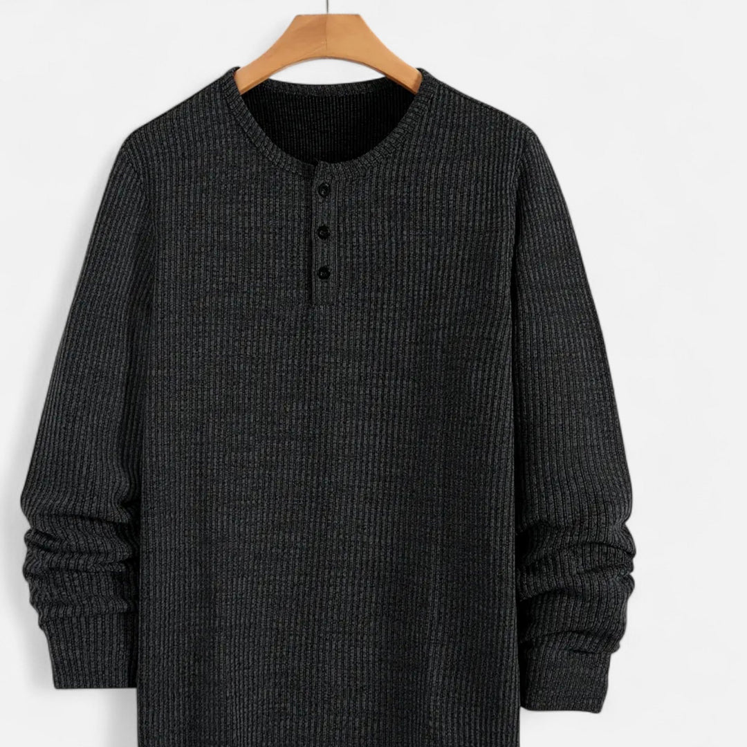 Detailed view of men's cable-knit henley sweater, long sleeve, showing intricate knit pattern & button front.