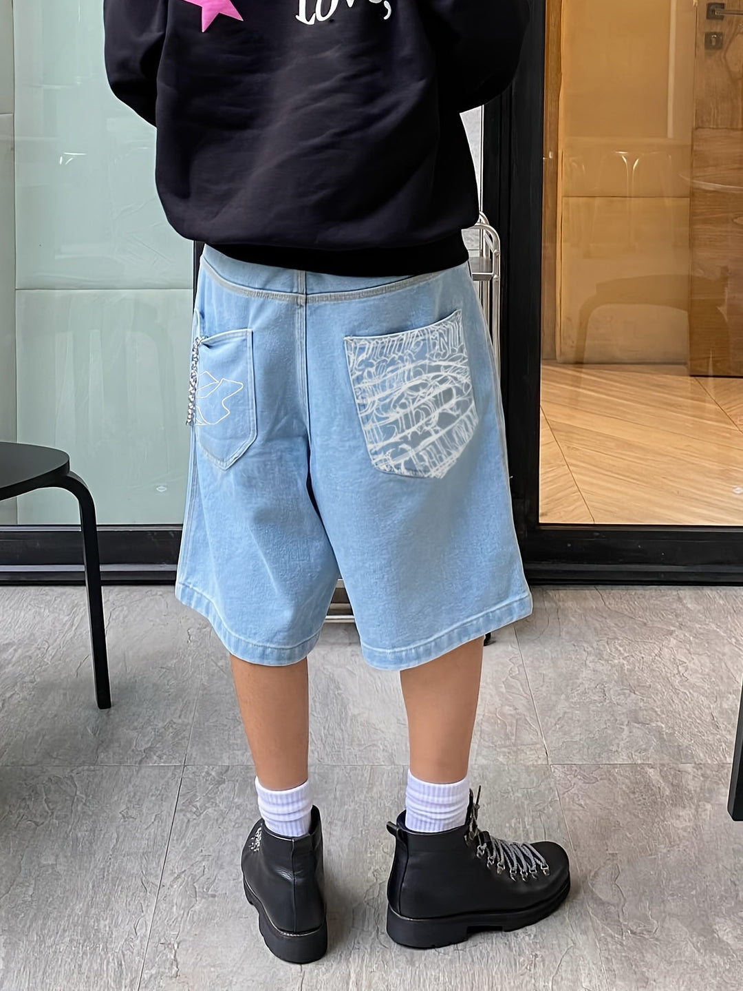 Stylish men's streetwear Bermuda shorts, loose fit denim with vibrant floral embroidery. Urban summer fashion.