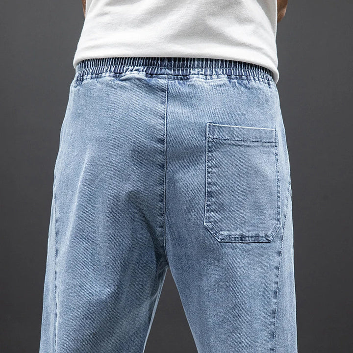 Close-up of men's jogger jeans featuring elastic drawstring waist and relaxed fit