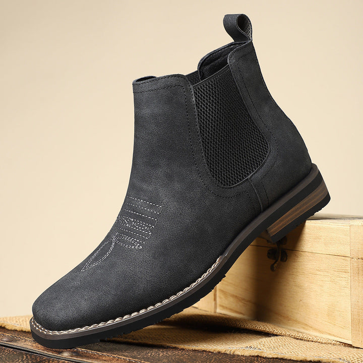 Side view of men's sleek black Chelsea boots, showcasing elastic goring and sturdy pull-tab.