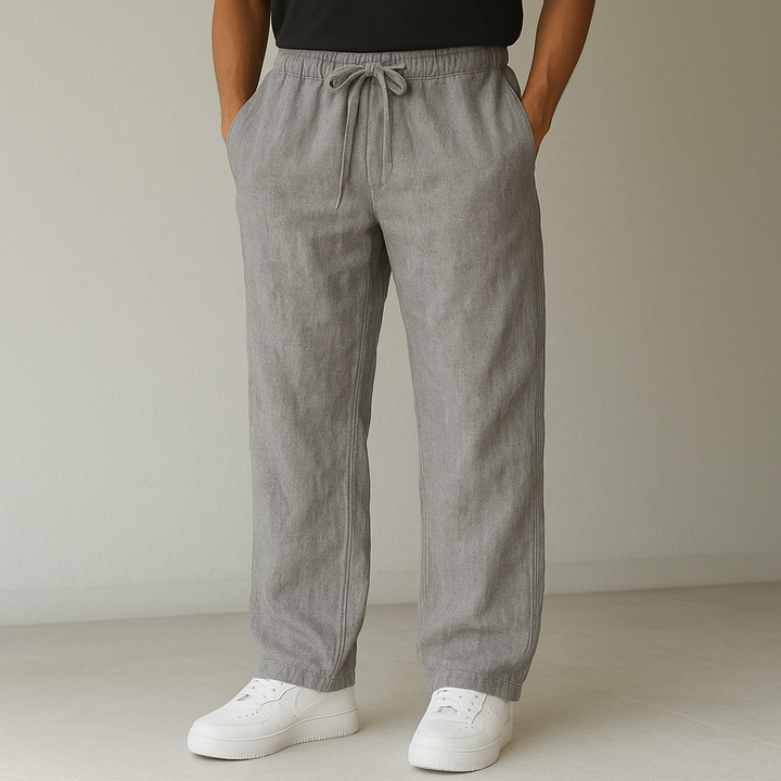 Close-up of men's sand-colored relaxed linen trousers, showcasing the drawstring waist and fabric texture.