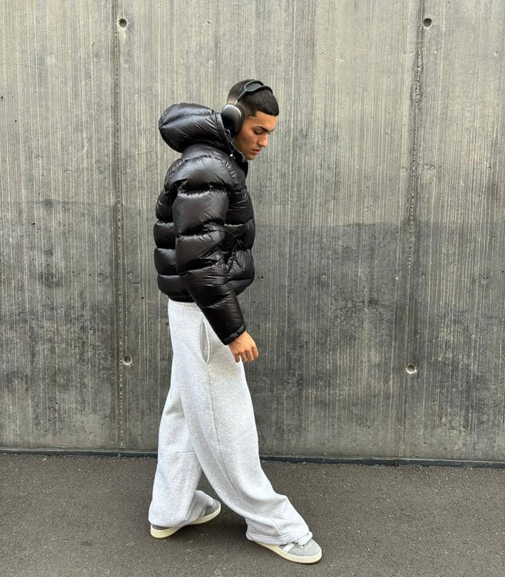 Side view of a men's shiny puffer jacket with hood, showcasing trendy street style outerwear.