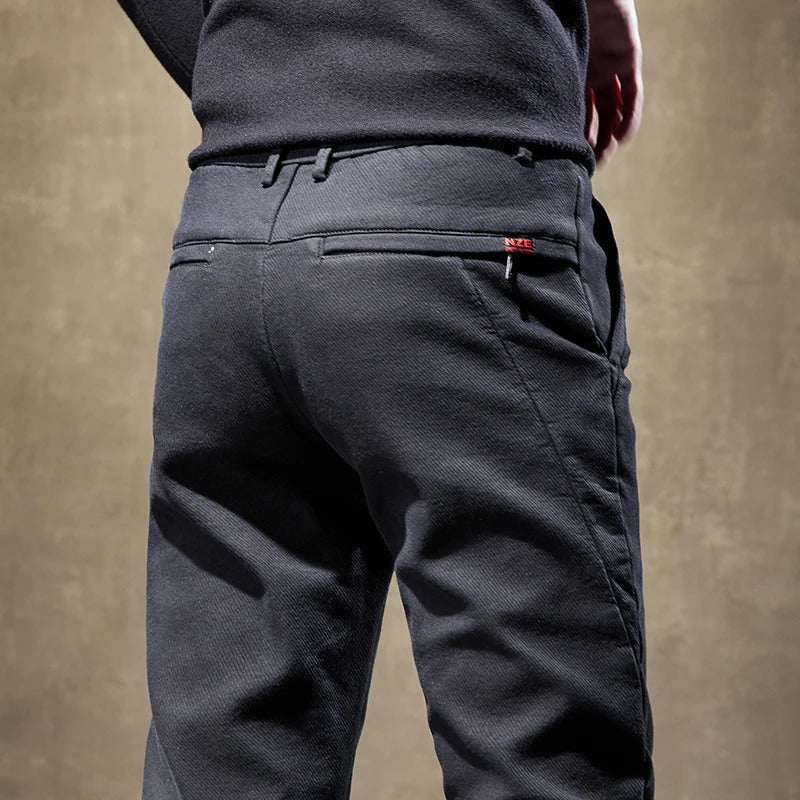 Stack of various colored men's slim-fit casual chino pants, showing their versatility in fashion.