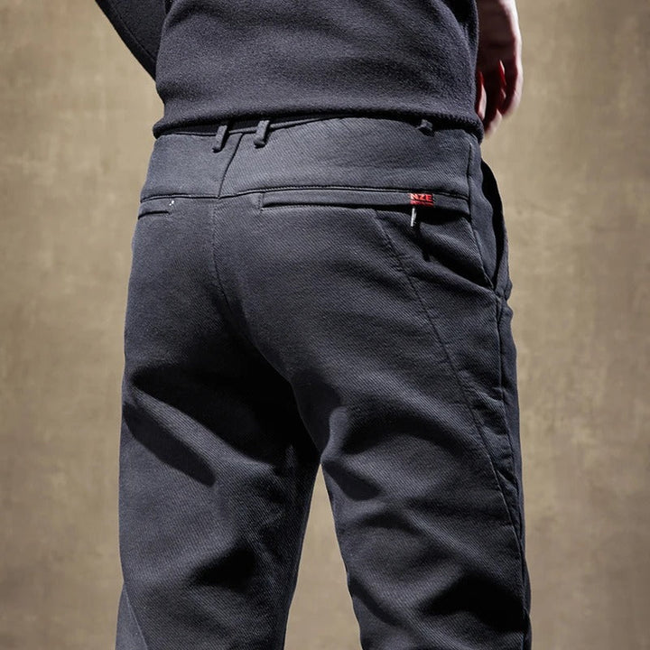 Stack of various colored men's slim-fit casual chino pants, showing their versatility in fashion.