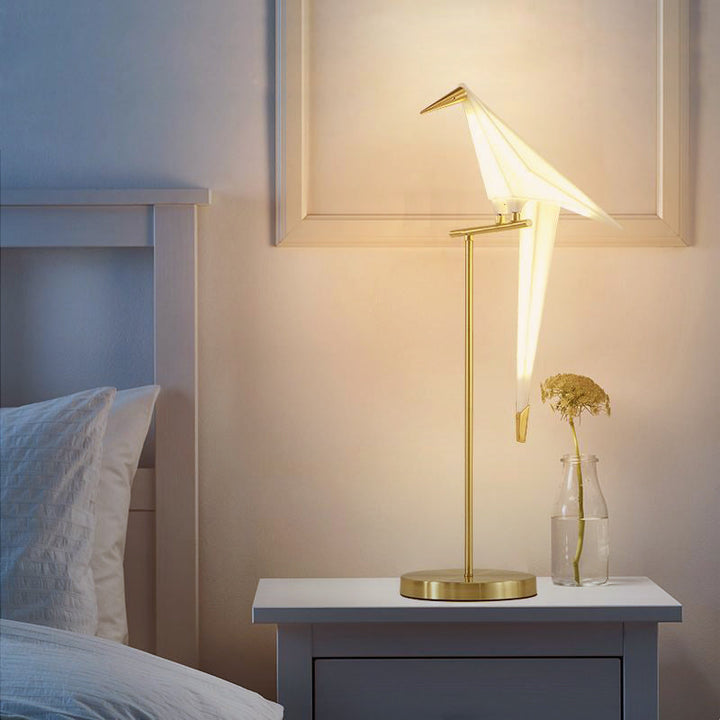 Elegant white origami bird table lamp with magnetic attachment, casting ambient LED light for modern interiors.