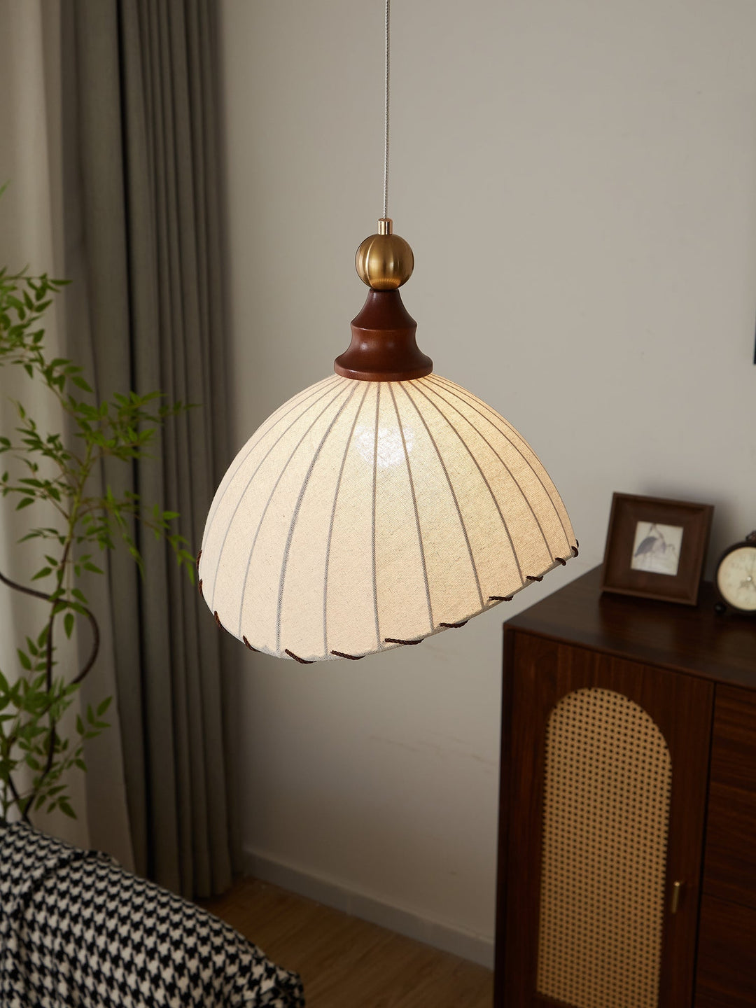 Modern lighting fixture: pleated fabric pendant, gold finish, wood accent, elegant design.