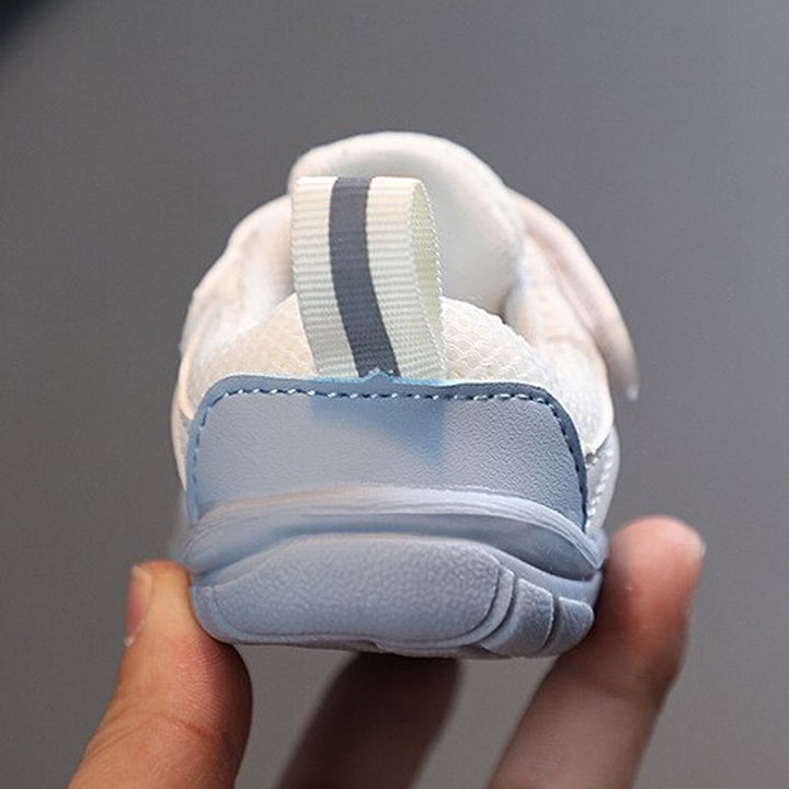 Toddler taking first steps in comfortable, flexible barefoot shoes, enhancing natural foot development.
