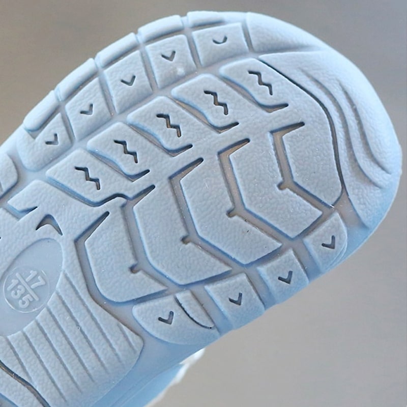 Infant's feet in soft, flexible barefoot shoes, supporting natural movement and healthy development.