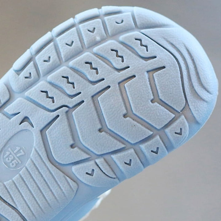 Infant's feet in soft, flexible barefoot shoes, supporting natural movement and healthy development.