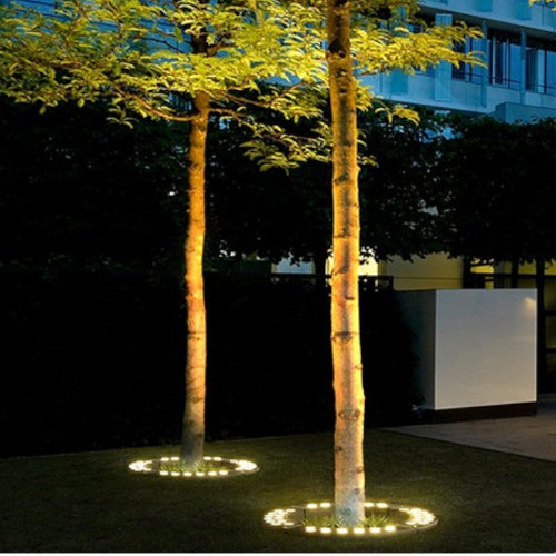 "Outdoor LED spotlights softly lighting tree bases with warm white glow, enhancing garden aesthetics with elegant aluminum de