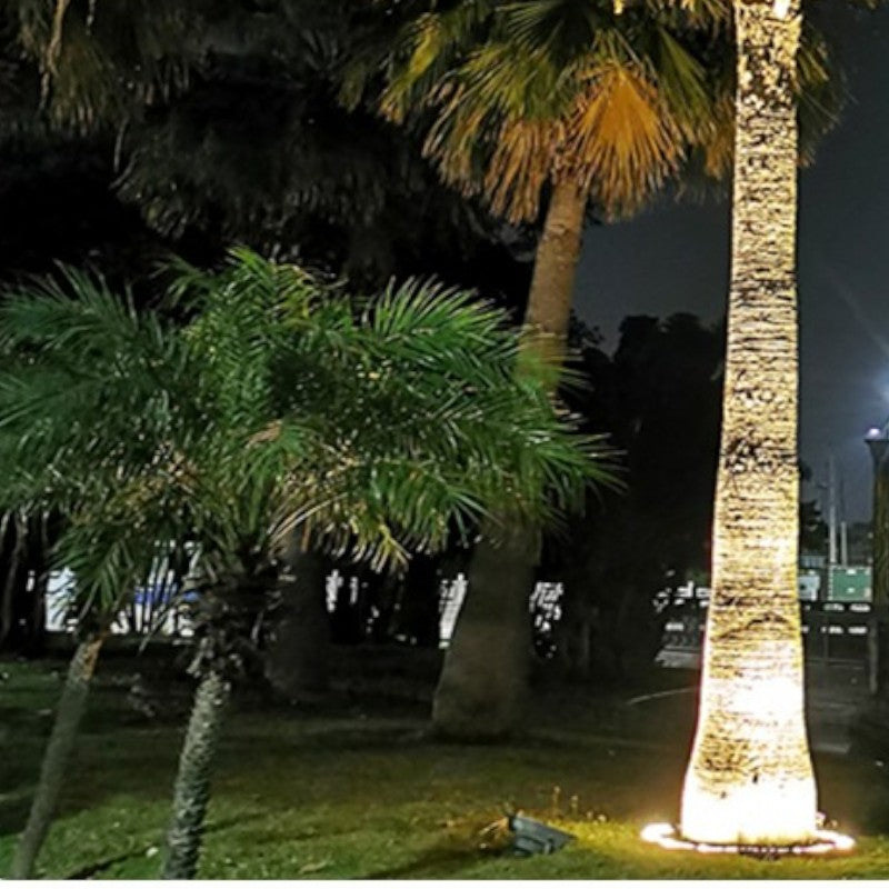 "Outdoor LED spotlights softly lighting tree bases with warm white glow, enhancing garden aesthetics with elegant aluminum de