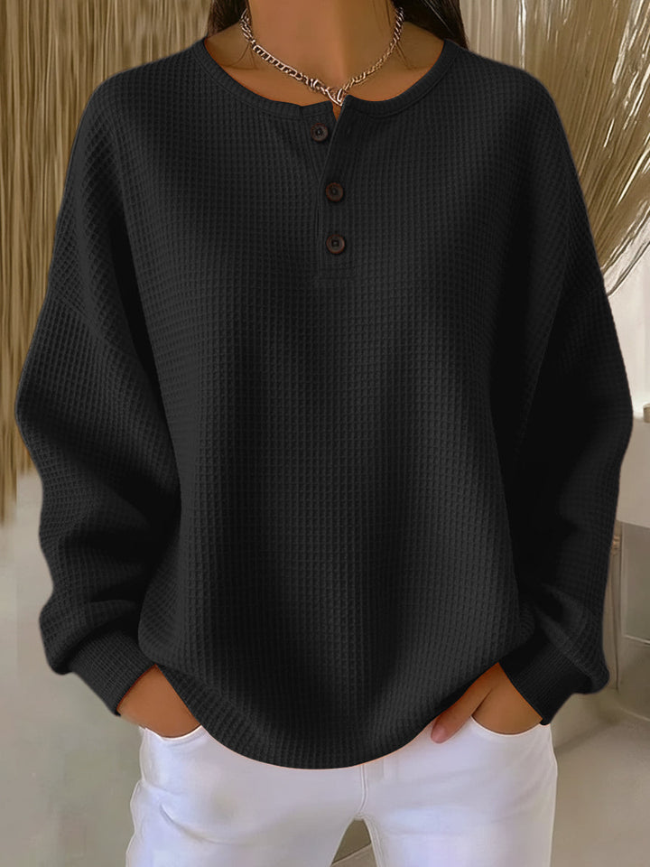 Stylish women's black waffle knit Henley top, a classic long sleeve piece for comfortable everyday wear.