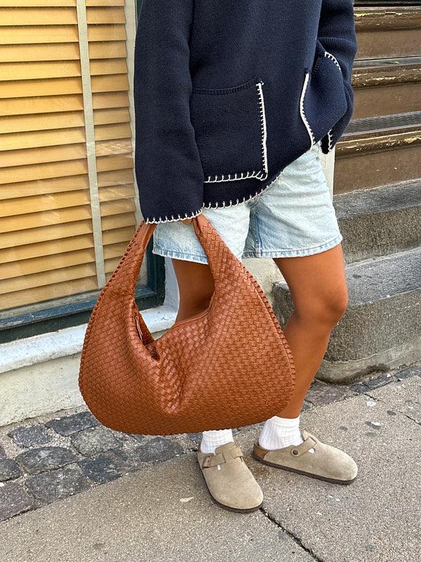 Trendy women's shoulder bag: soft vegan leather, woven design, comfortable slouch style.