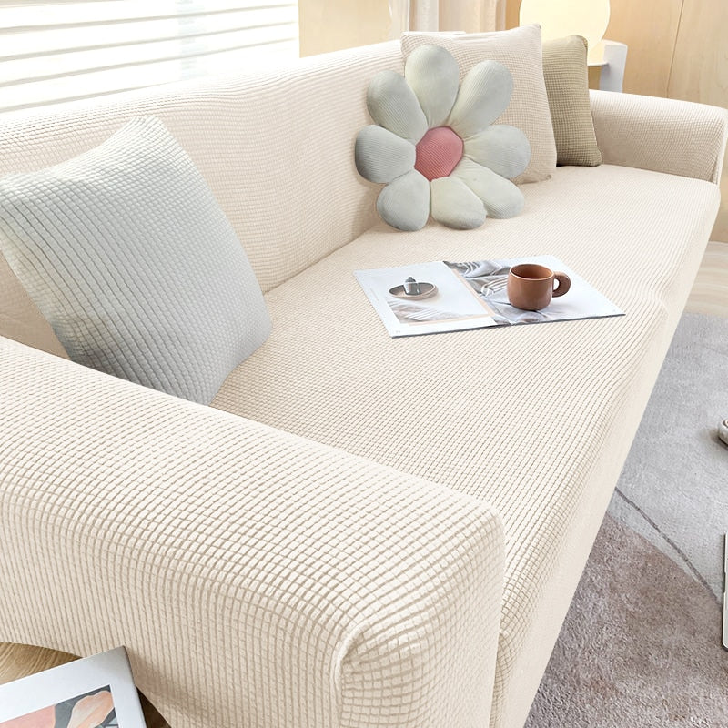 Textured stretch sofa cover in a modern living room, protecting furniture from spills and pets