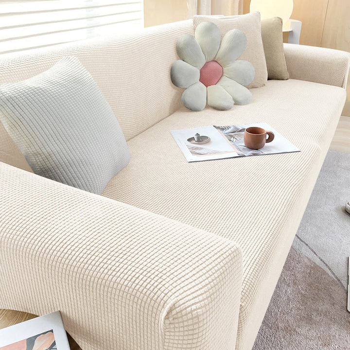 Textured stretch sofa cover in a modern living room, protecting furniture from spills and pets