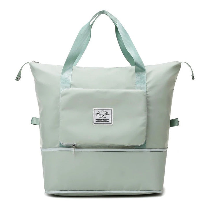 Traveler carrying a black waterproof expandable weekender bag at the airport, perfect as carry-on luggage.
