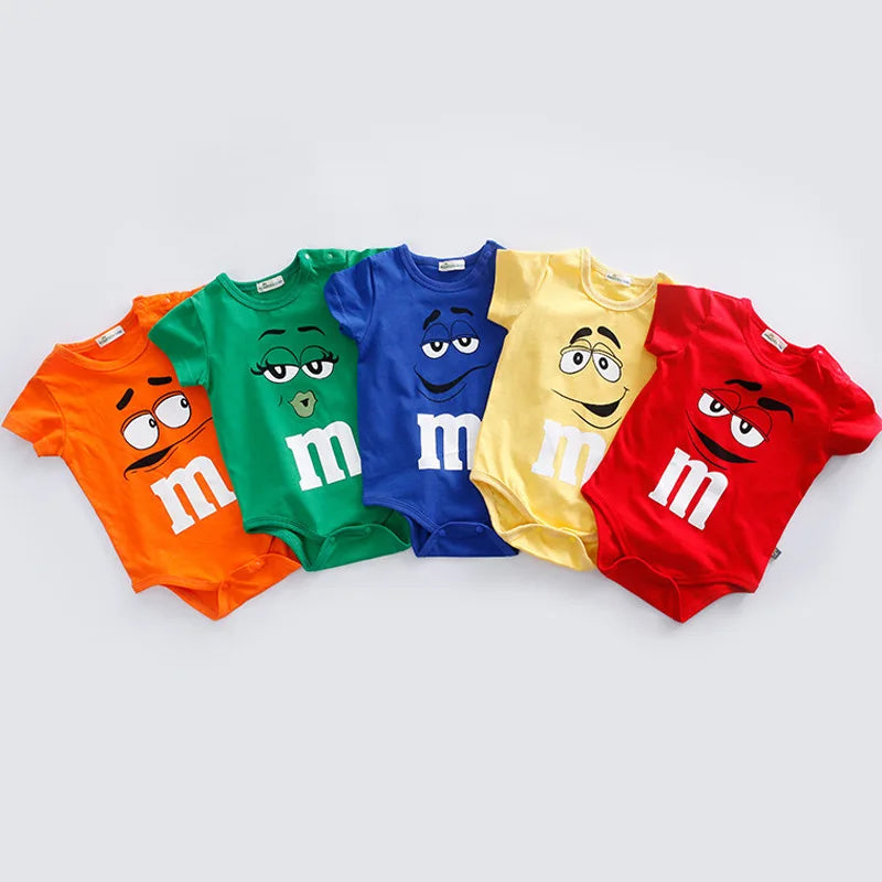 Close-up of a colorful baby romper featuring cheerful M&M faces print. Short sleeve infant & toddler summer jumpsuit.