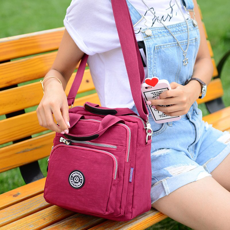 Unisex water-resistant crossbody bag, black, worn by a model, showing adjustable strap and front pocket.