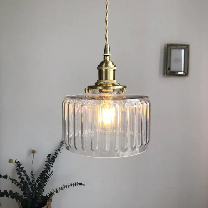 Vintage cylindrical glass pendant lamp casting warm glow; elegant centerpiece for home decor. Perfect for living and dining a