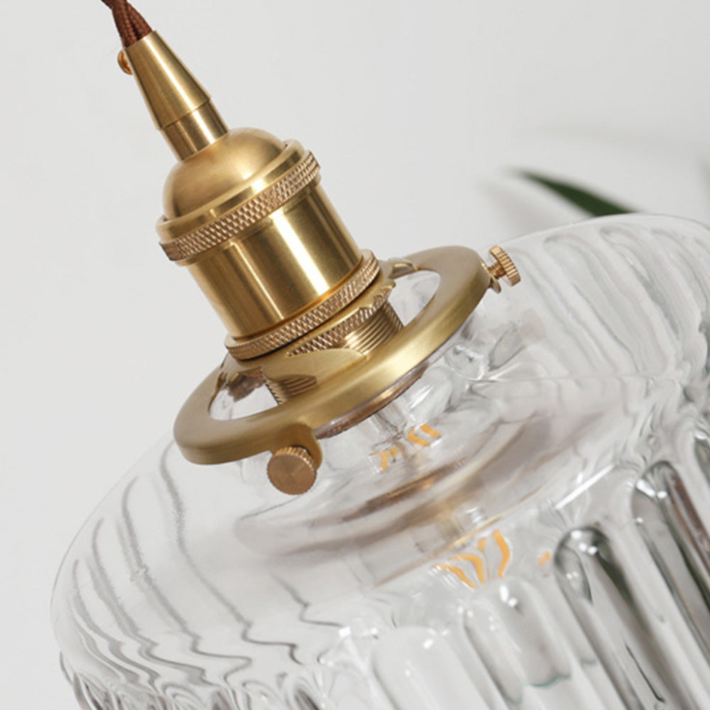 Vintage cylindrical glass pendant lamp casting warm glow; elegant centerpiece for home decor. Perfect for living and dining a