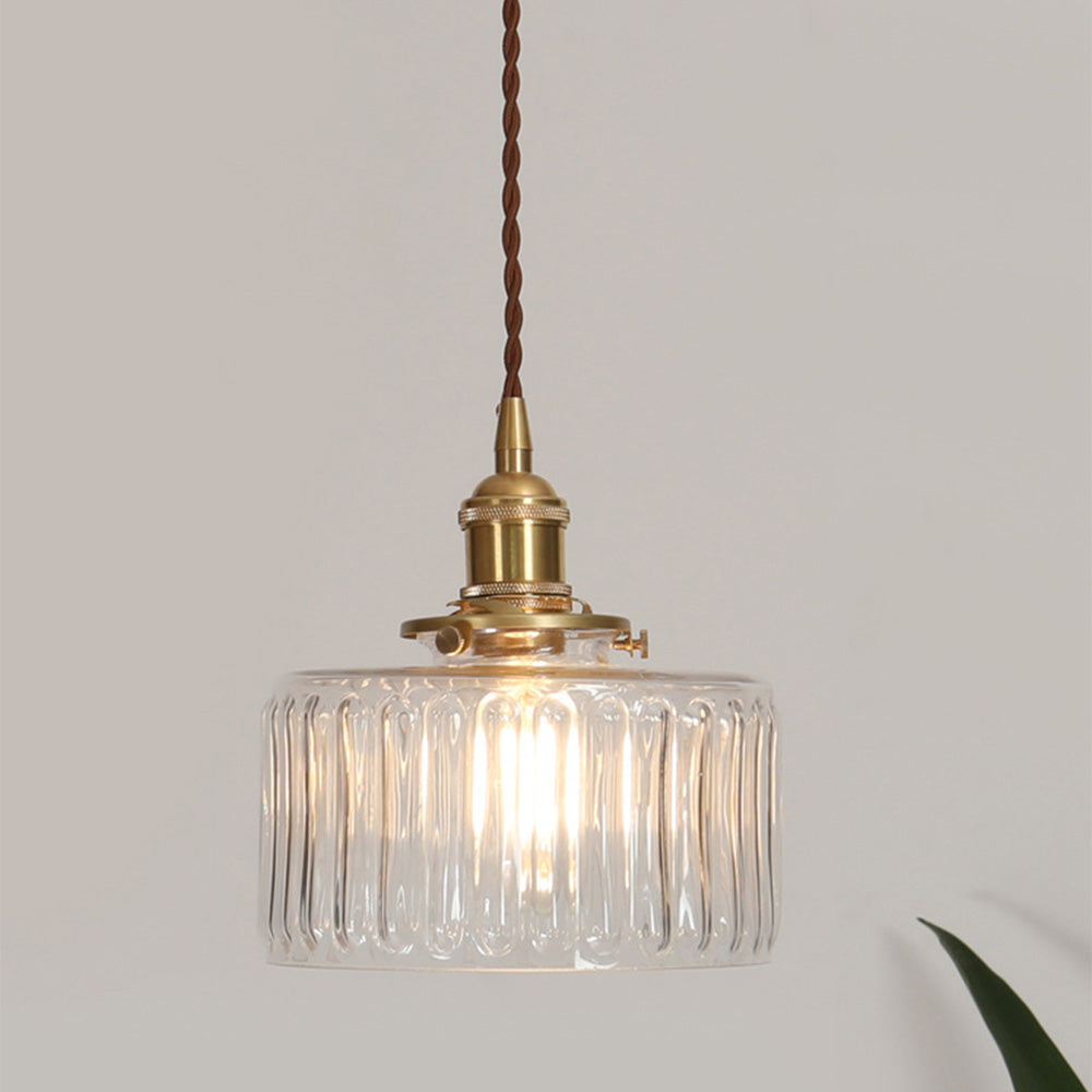 Vintage cylindrical glass pendant lamp casting warm glow; elegant centerpiece for home decor. Perfect for living and dining a