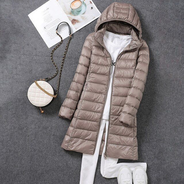 Side profile of a women's warm, long puffer jacket showing the detachable hood and down fill
