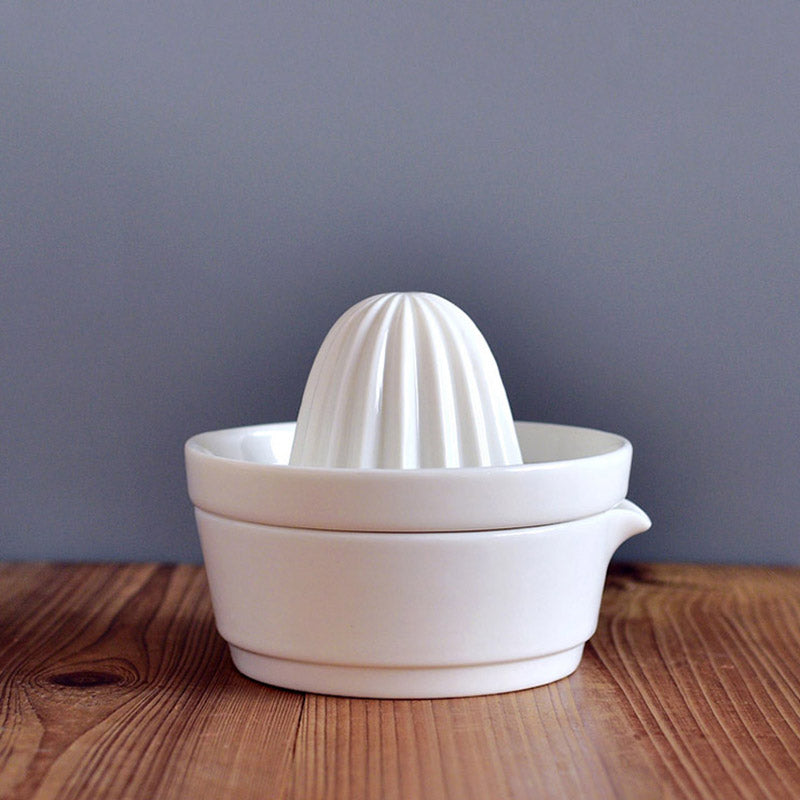 White ceramic manual citrus juicer, perfect for squeezing fresh lemon, lime, or orange juice.