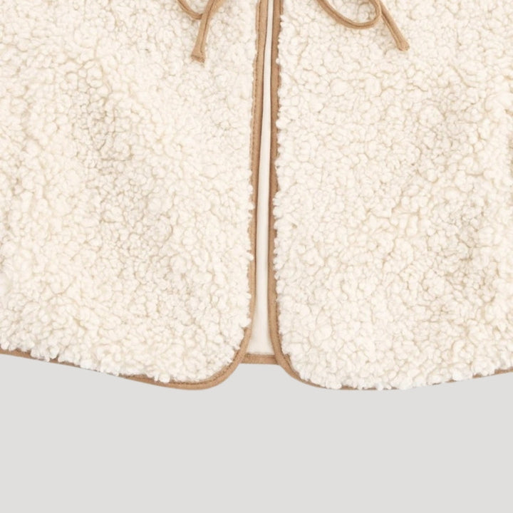 Detail of the tie-front closure on a women's lightweight beige vest, emphasizing comfort and style