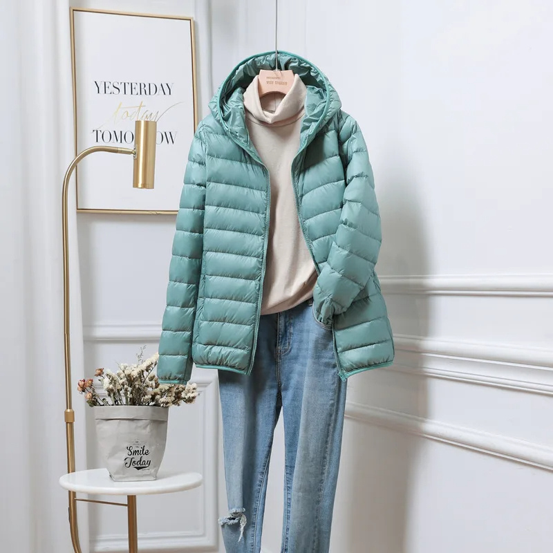 Front view of a women's green hooded zip puffer jacket with pockets, warm & casual