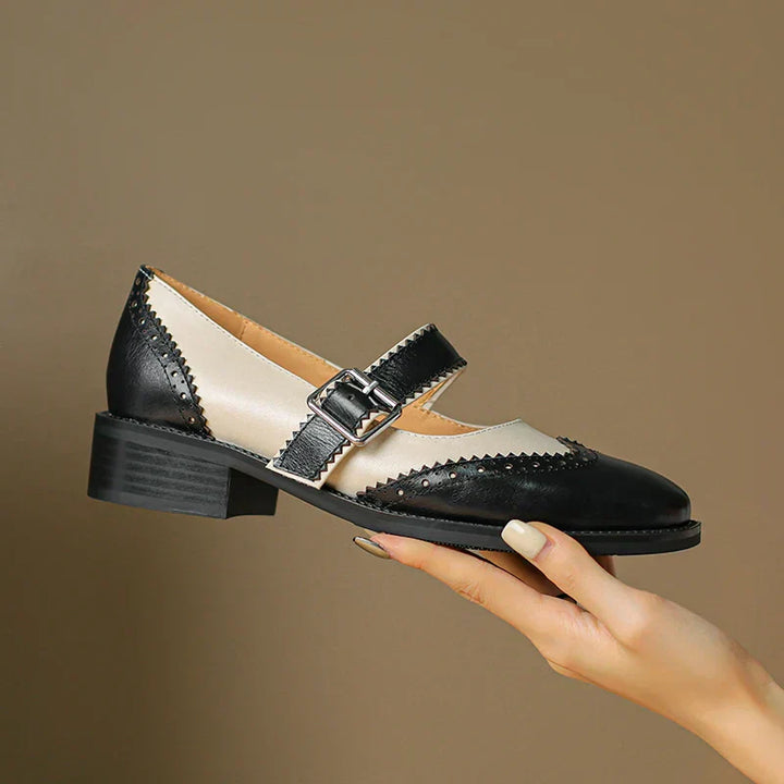 Pair of women's leather Mary Jane shoes in a classic black, featuring an adjustable buckle strap and flat heel.