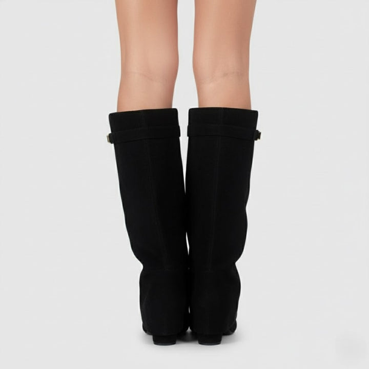Close-up of a women's black leather thigh-high boot, highlighting the buckle detail.