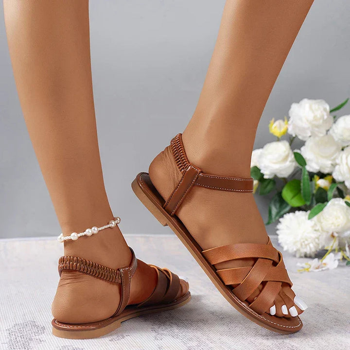 Stylish women's summer flat sandals, brown, featuring cross straps & an elastic heel for all-day comfort.