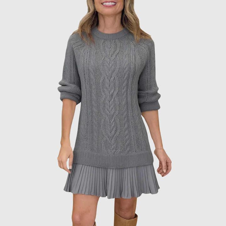 Back view of a women's cable knit dress with a stylish pleated skirt detail.