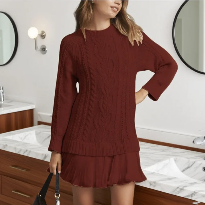 Detailed view of the pleated hem on a women's long sleeve cable knit sweater dress.