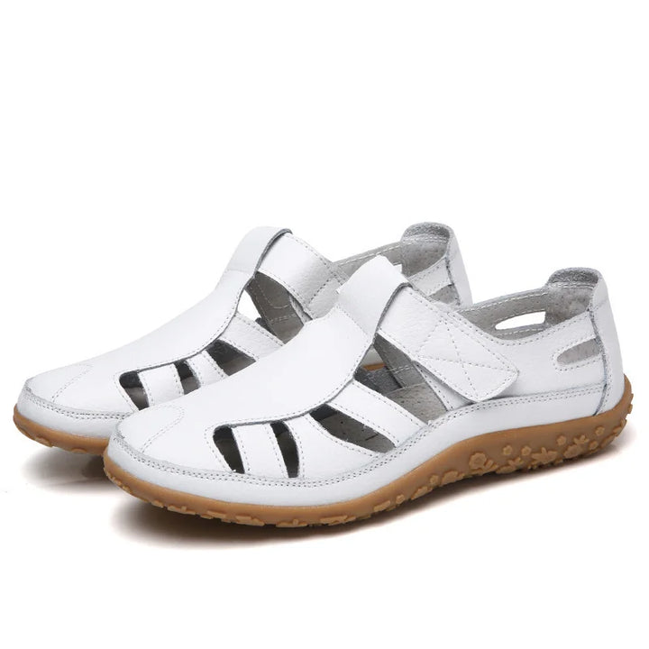 Pair of women's spring footwear: flat, open-toe sandals with unique laser-cut designs.