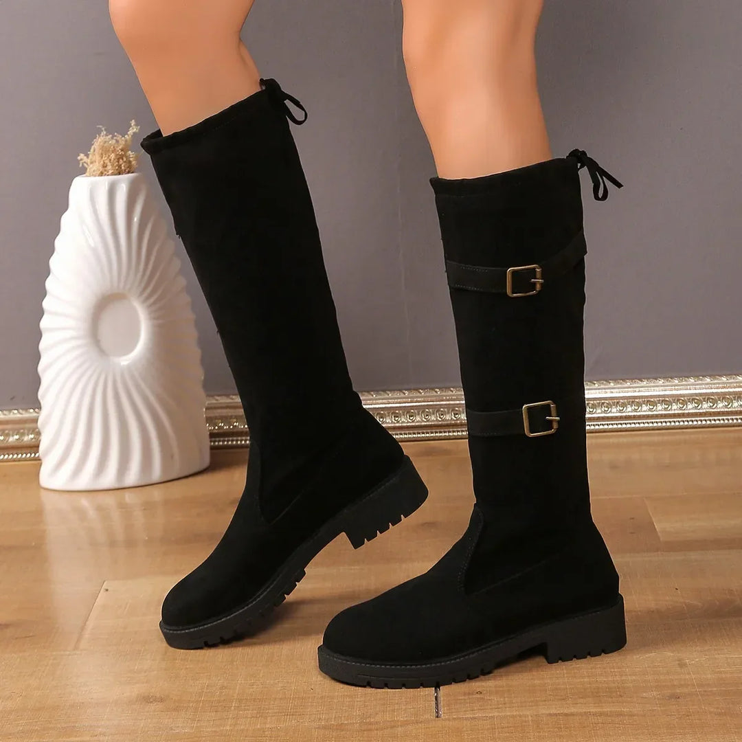 Close-up of a women's tall suede boot highlighting the elegant buckle and texture.