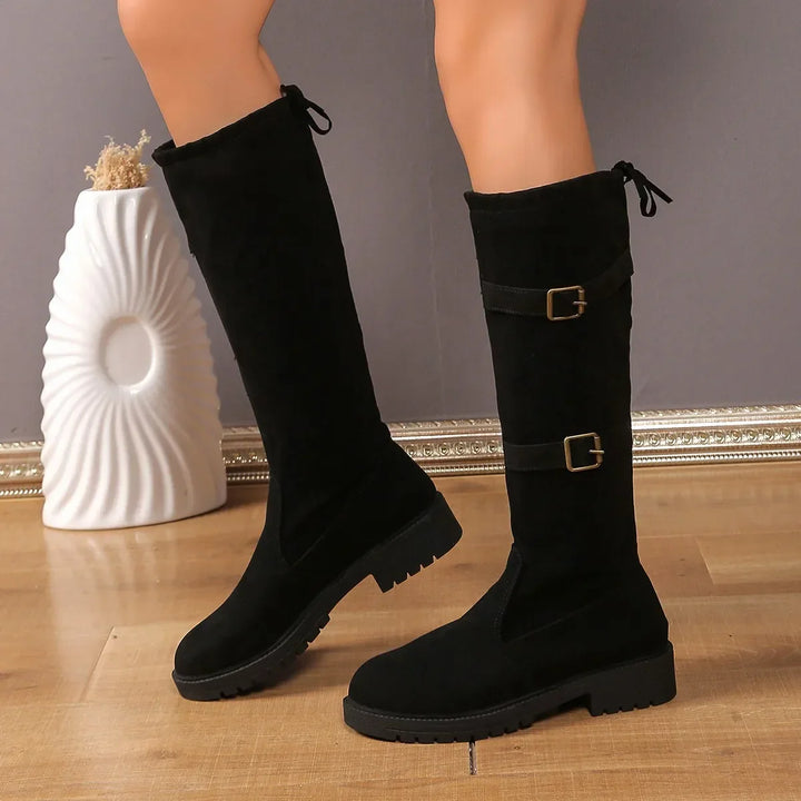 Close-up of a women's tall suede boot highlighting the elegant buckle and texture.