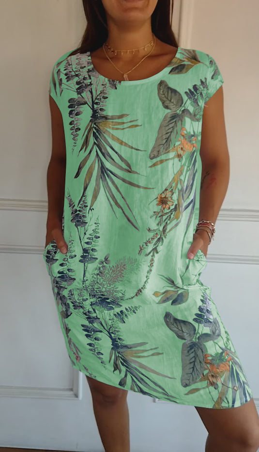 Woman wearing a leaf print short sleeve casual summer dress, perfect for warm weather or vacation.