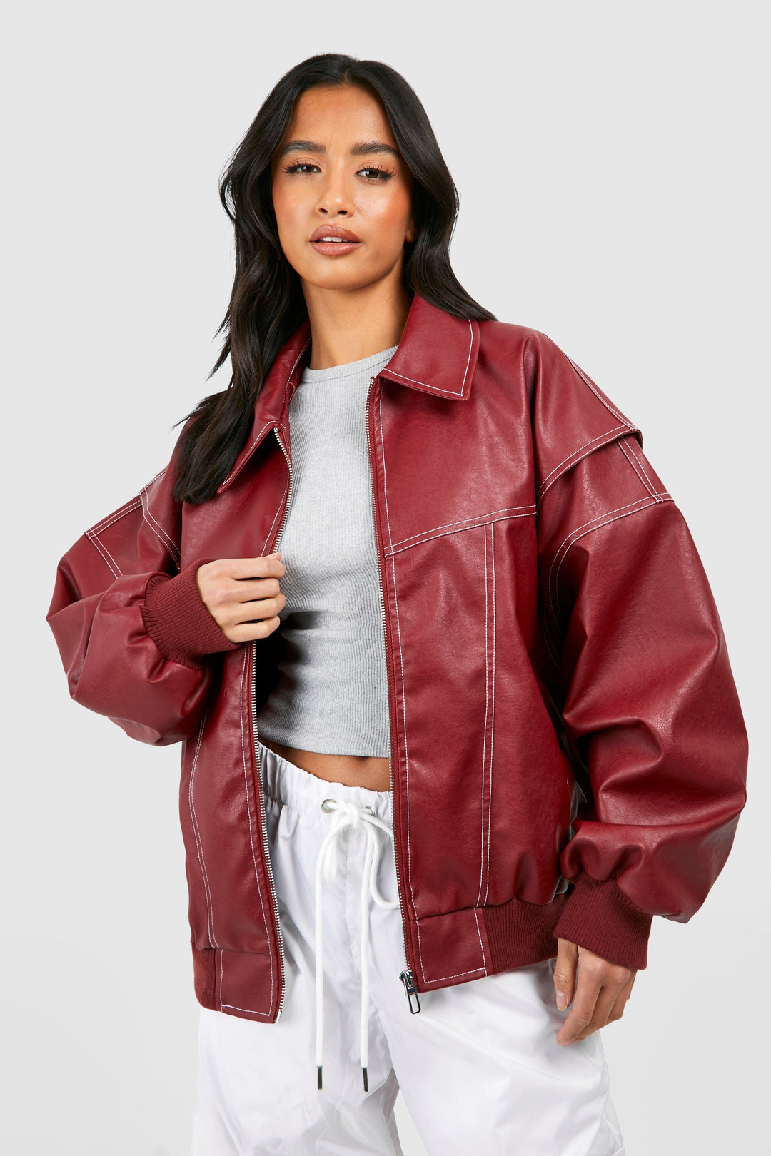 Close-up of a woman wearing a classic brown faux leather bomber jacket, elegant and modern