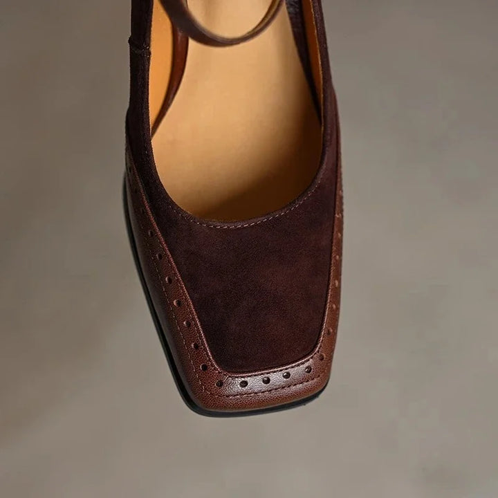 Stylish women's black leather pumps with a secure ankle strap, low heel, and elegant square toe design.