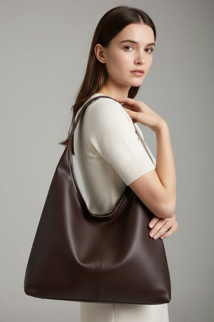 Close-up of a brown faux leather tote bag with subtle texture, showcasing classic handbag details and stitching.