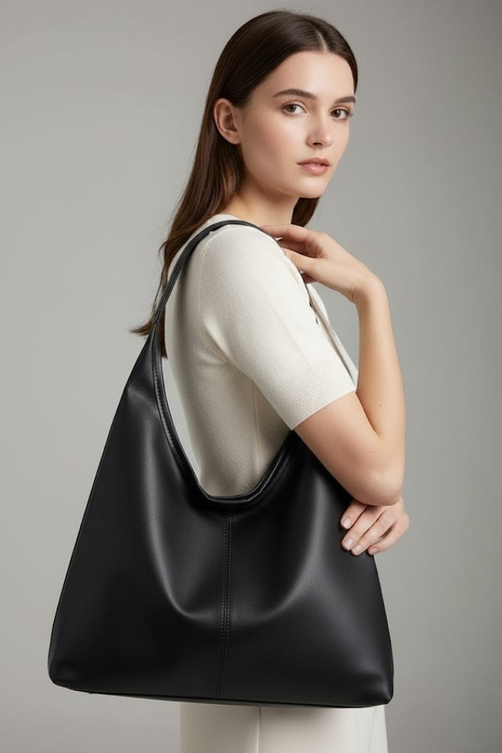 Detail shot of the secure zipper closure and metal accents on a black faux leather women's tote bag.