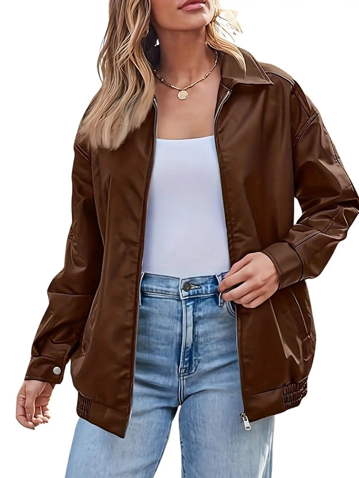 Detailed shot of zipper and ribbed cuffs on a women's black faux leather bomber jacket
