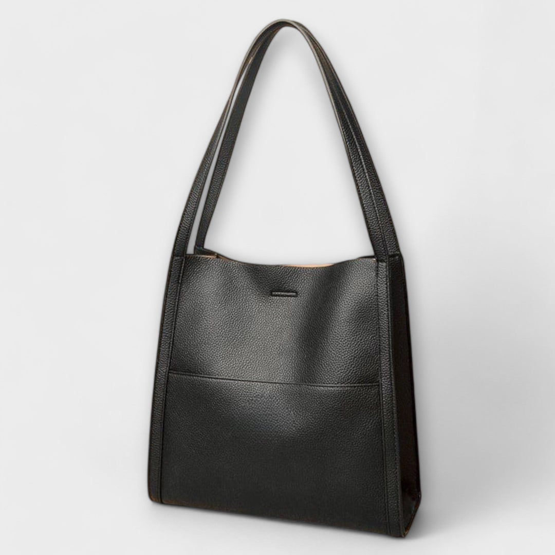 Detail of the comfortable shoulder strap on a women's classic structured faux leather bag.