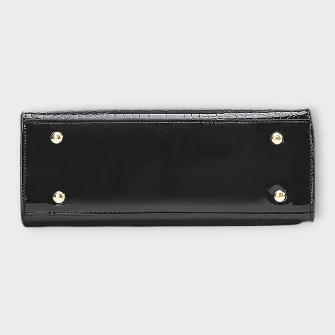 Women's structured black handbag, side view, showcasing its elegant profile and sturdy top handle.