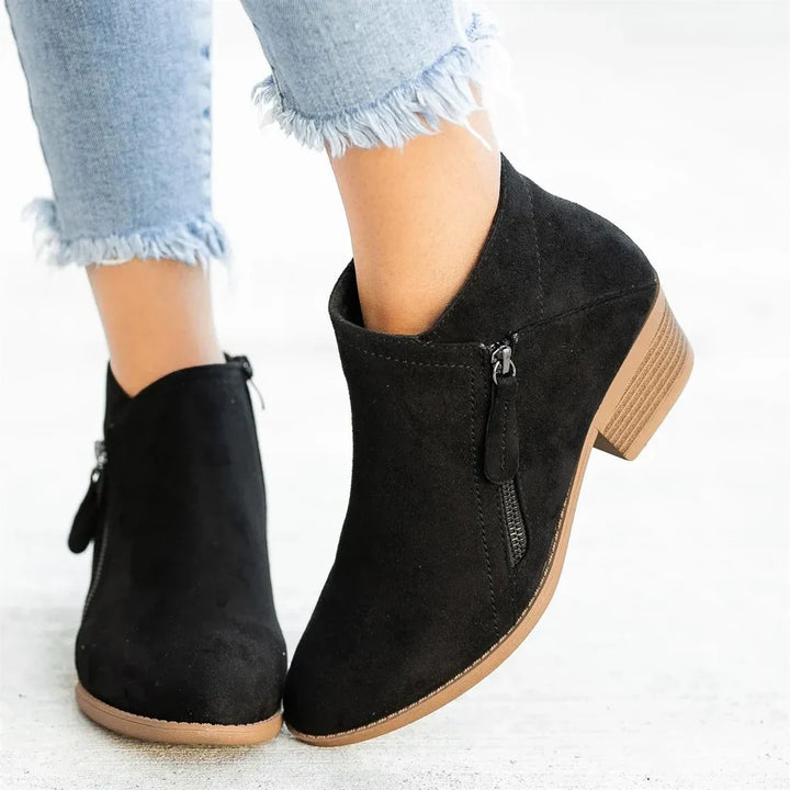Close-up of new women's comfortable leather ankle boots with detailed side zipper and durable non-slip sole.