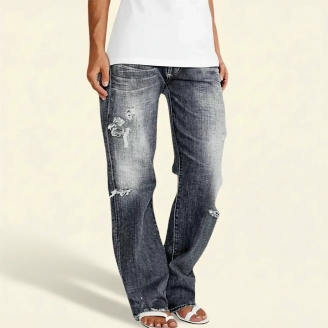 Close-up of the distressed detail on women's dark denim high-rise straight leg jeans.