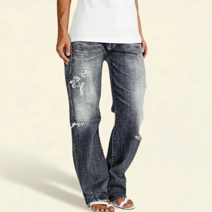 Close-up of the distressed detail on women's dark denim high-rise straight leg jeans.
