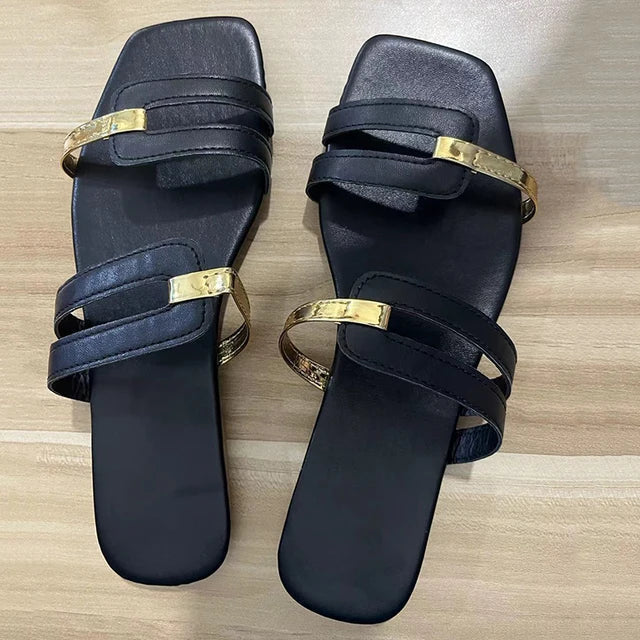 Open-toe women's flat sandals with two straps and sophisticated gold decorative elements.